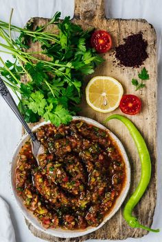 a wooden cutting board topped with a bowl filled with food and garnished with cilantro