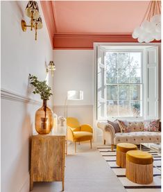 a living room filled with furniture next to a large window covered in pink and yellow