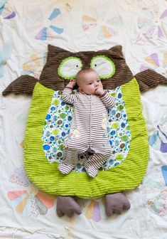 a baby laying on top of an owl shaped blanket