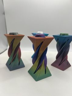 three colorful vases sitting next to each other on a table