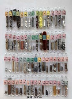 an array of different types and sizes of beads in plastic containers on a white surface