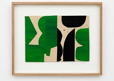 an abstract painting with green and black shapes in a wooden frame on a white wall