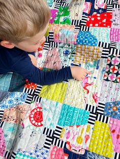 a little boy that is laying down on a quilt