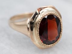 "This piece is unique in the fact that the head used to be a cufflink! The warm gold compliments the sparkling garnet, with undertones of canary and burgundy. Material: 10K Yellow Gold Gem: Garnet 2.36 Carats Gem Measurements: 6.8 x 8.9 mm, Oval  Size: 3.50 Marks: \"10K\" on inside band SKU #: A23335 Each piece has been identified and graded by a Graduate Gemologist who has been certified by the Gemological Institute of America (GIA). We have four brick and mortar storefronts in Maine, Massachusetts and New Hampshire and have been in business for over 25 years! Please visit our Shop's About Page or our website for more information about our jewelry. For questions about diamond grading, we recommend the Gemological Institute of America (GIA) who were the founders of the 4C's. If you have an Aquamarine Solitaire Ring, Opal Solitaire Ring, Garnet And Gold, Gold Solitaire Ring, Solitaire Setting, Red Band, Gold Gift, Rhodolite Garnet, Jewelry Companies