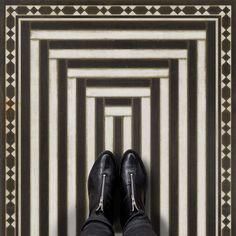 a pair of black shoes sitting on top of a floor next to a striped wall