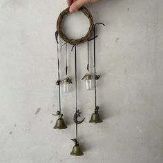 a hand is holding an old fashioned wind chime with three bells attached to it