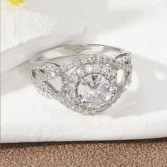 a white diamond ring sitting on top of a table next to a napkin and flower