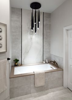 a bathroom with a bathtub, towel rack and chandelier hanging from the ceiling