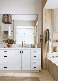 a large bathroom with white cabinets and drawers, along with a bathtub in the background