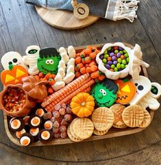 a wooden tray filled with halloween treats and candies on top of a wood table