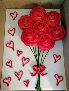 a bouquet of red roses sitting on top of a white box with hearts drawn on it