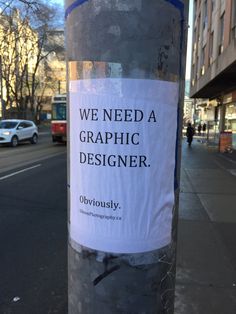 a sign on a pole that says we need a graphic designer