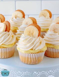 cupcakes with banana slices and cream frosting on a white cake platter