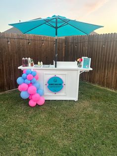 a table with balloons and an umbrella in the back yard at a birthday party or baby shower