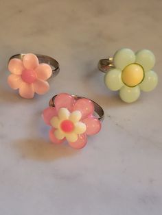 Simple flower rings! Your choice of style, all made with stainless steel adjustable bands.  Available in: Pale pink with pastel pink center (Top left of 1st photo) Pastel pink with white and hot pink center (Bottom middle of 1st photo) Mint with buttery yellow center (Top right of 1st photo) Glued down with gorilla glue and tested ensure the plastic cabochons don't come off. I would still try to avoiding pulling on the flowers with great force as this may loosen/remove the cabochon. I found that Spring Pink Flower Ring Gift, Adjustable Pink Flower Shaped Rings, Pink Ring For Spring Gift, Pink Ring As Spring Season Gift, Spring Gift Pink Ring, Spring Gift Pink Rings, Pink Rings Suitable For Spring Gift, Cute Pink Round Rings, Handmade Vintage Pink Rings