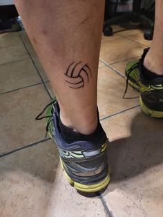 a person's foot with a tattoo on their left leg and running shoes in the background