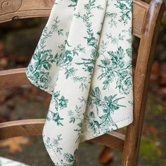 a green and white floral print table cloth on a wooden chair