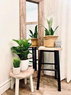 two potted plants sit on stools in front of a mirror and wooden table