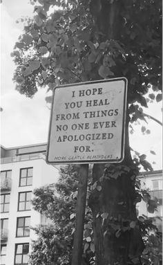 a sign that is on the side of a pole in front of a tree and building