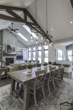 a dining room table with chairs and lights hanging from the ceiling in front of a fireplace