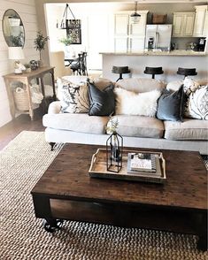 a living room filled with furniture and pillows on top of a coffee table in front of a window