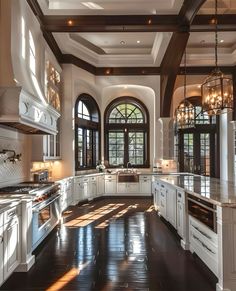 a large kitchen with lots of white cabinets and wood trimmings on the ceiling