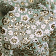 the fabric has gold and white flowers on it, along with other material that is green