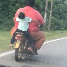 a man riding on the back of a motorcycle with a child sitting on it's back