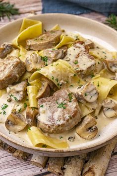 a white plate topped with pasta covered in mushrooms