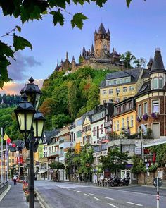 a city street lined with lots of tall buildings next to a lush green forest covered hillside