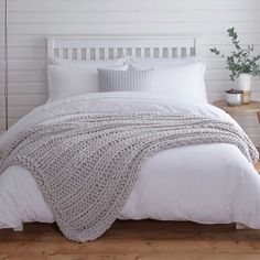 a bed with white sheets and pillows in a room next to two pictures on the wall