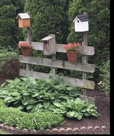 a wooden fence with flowers and bird houses on it's posts in the middle of a garden