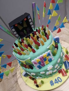 a birthday cake with colorful decorations and streamers on it's side, sitting on a table