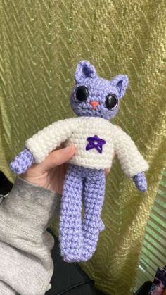 a crocheted purple cat holding a white object in it's right hand