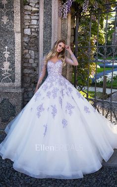 a woman in a white and purple wedding dress standing next to an iron gate with flowers on it