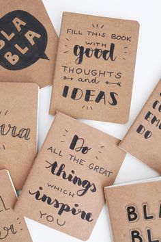 six handmade notebooks with black ink on brown paper, each containing different phrases