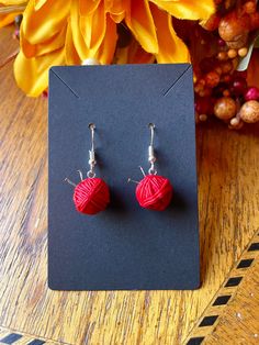 a pair of red heart shaped earrings sitting on top of a table