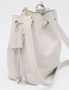 Introducing our elegant small Authenticity purse, crafted from genuine leather that exudes sophistication and timeless style. The detachable and adjustable cross body shoulder strap ensures versatile carrying options for any occasion. This bucket bag, with its two pull double cord drawstrings, is the perfect blend of luxury and practicality. ETHICALLY HANDCRAFTED BY STIVALI MEASUREMENTS: Length: 7" Width: 5" Height: 8" FEATURES/MATERIALS: Smooth leather Detachable & Adjustable cross body shoulde Luxury Cream Bucket Bag In Pouch Shape, Luxury Cream Pouch Bucket Bag, Luxury Cream Bucket Bag For Travel, Leather Bucket Bag For Everyday Luxury, Luxury Cream Bucket Bag For Daily Use, Classic White Bucket Bag With Leather Handles, Versatile Smooth Grain Crossbody Bucket Bag, Classic Cream Bucket Bag, Luxury Cream Crossbody Bucket Bag