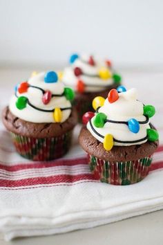 christmas light cupcakes with white frosting and colorful candies are on a striped napkin