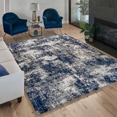 a living room with blue chairs and a white rug on the hardwood floor, in front of a fireplace