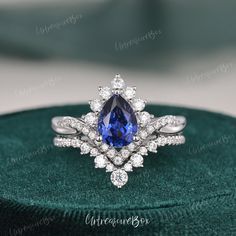 a blue and white diamond ring sitting on top of a green velvet box