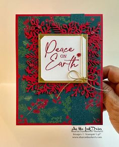 a hand holding up a card with the words peace on earth in red and green