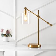 a table lamp on a white shelf next to a potted plant and vase with flowers