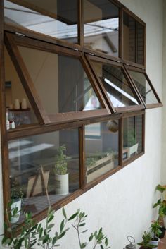 an open window on the side of a building with potted plants in front of it