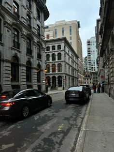 two cars are parked on the side of the road in front of some tall buildings