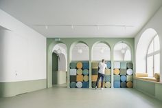 a man standing on top of a colorful wall in an empty room next to windows