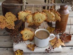 a cup of coffee sitting on top of a white napkin next to some autumn leaves