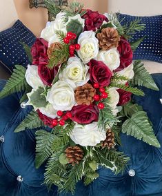 a bridal bouquet with white and red flowers on a blue velvet cushioned chair