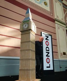 a man standing next to a tall wooden clock tower