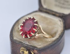 A glorious vintage Early-to-Mid-Century ring with a chunky ruby-red stone, and statement gold band. Stamped for 9ct gold on the inside. - UK Size - Q - US Size  - 8 Weight - 3.5 grams -------------------- All boxes in the photographs are for display purposes only. Please be aware there will be marks and wear commensurate with age. Feel free to contact me with any questions. Antique Red Ruby Ring In 14k Gold, Vintage 14k Gold Ruby Birthstone Ring, Vintage 14k Gold Ruby Ring For Formal Occasions, Vintage Yellow Gold Ruby Ring Birthstone, Vintage Yellow Gold Ruby Birthstone Ring, Vintage Formal Birthstone Jewelry, Antique Red Rings With Prong Setting, Antique Red Ring With Prong Setting, Vintage Ruby Jewelry Hallmarked